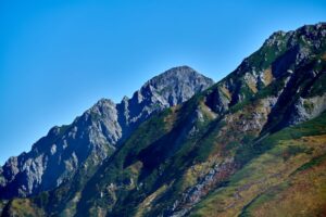 青空を背景に、岩壁と鋭い稜線がそびえる剱岳の山容