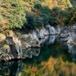 峡谷の岩壁と川面に鮮やかに映り込む秋の木々