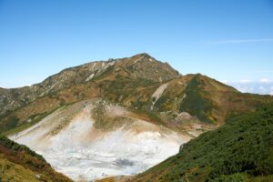 奥大日岳を背景に、下方には白い岩肌と噴気が立ち上る立山地獄谷が広がる光景