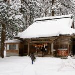 富山市岩峅寺の雄山神社。雪深い境内に佇む本殿に参拝者が歩いていく冬の風景。