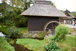 茅葺き屋根の水車小屋と小川、緑に囲まれた懐かしい日本の原風景。
