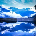 上高地の大正池から望む穂高連峰。雲と山が湖面に映り込む風景写真。