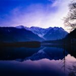上高地の大正池から望む穂高連峰。初冠雪の山並みが湖面に映る風景写真。