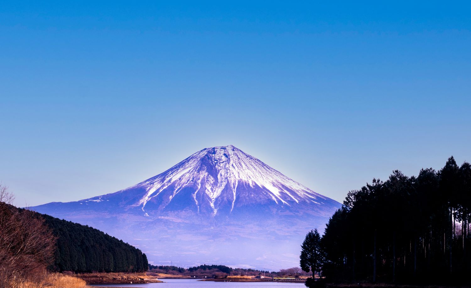 冬の田貫湖から見た富士山。雪を頂いた山と青空、湖面に映る静かな風景。