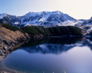 雪をいただいた立山連峰を背景に、みくりが池の水面に山並みが映り込む冬の景色