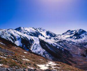 青空を背景に、雪をまとった立山連峰が稜線を連ねる初冬の風景