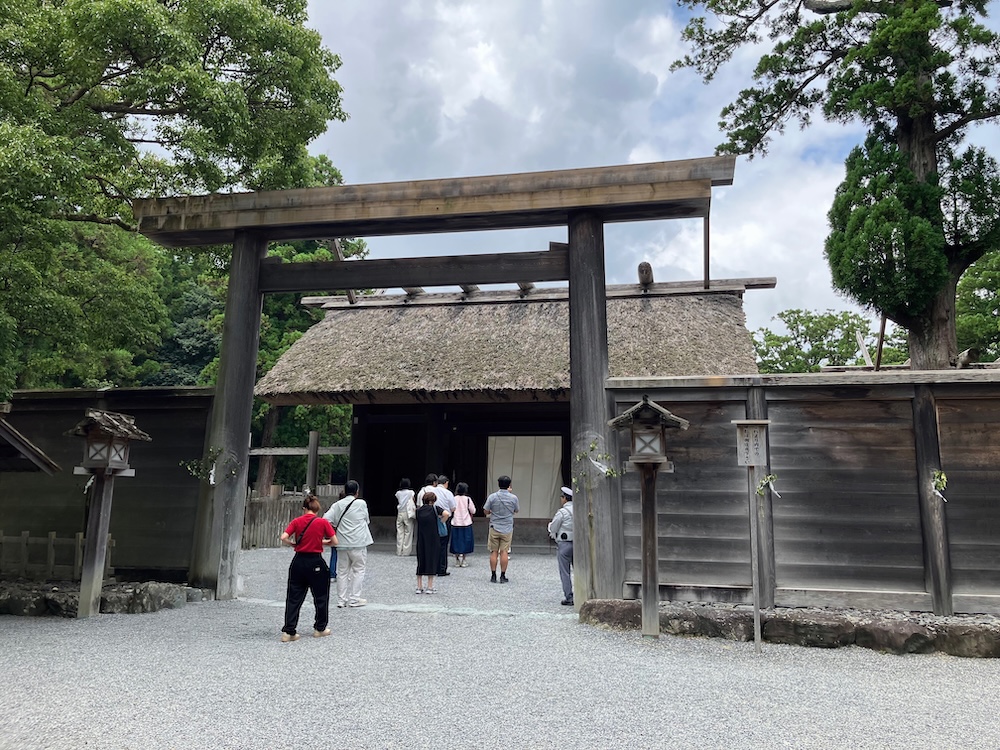 伊勢神宮外宮の御正殿を正面から撮影した写真。木造の鳥居と高い御垣に囲まれ、多くの参拝者が参道を進んでいる。