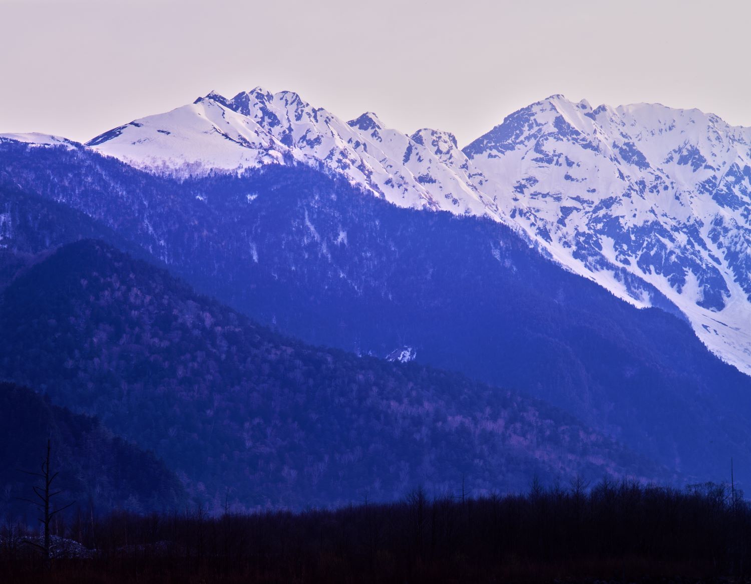 上高地から見た晩秋の西穂高連峰、雪を纏った山並みと沈む光の風景
